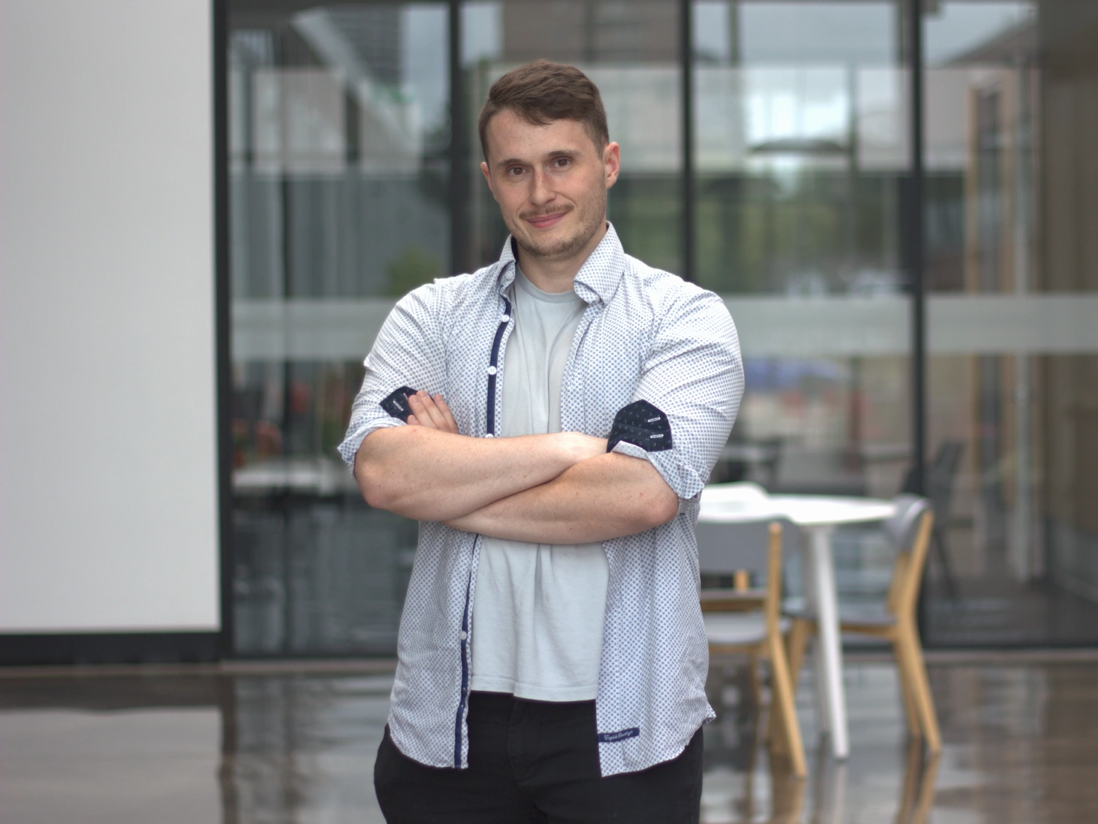 An image of Red Oxford Online's founder standing in a hall smiling, with his arms crossed.